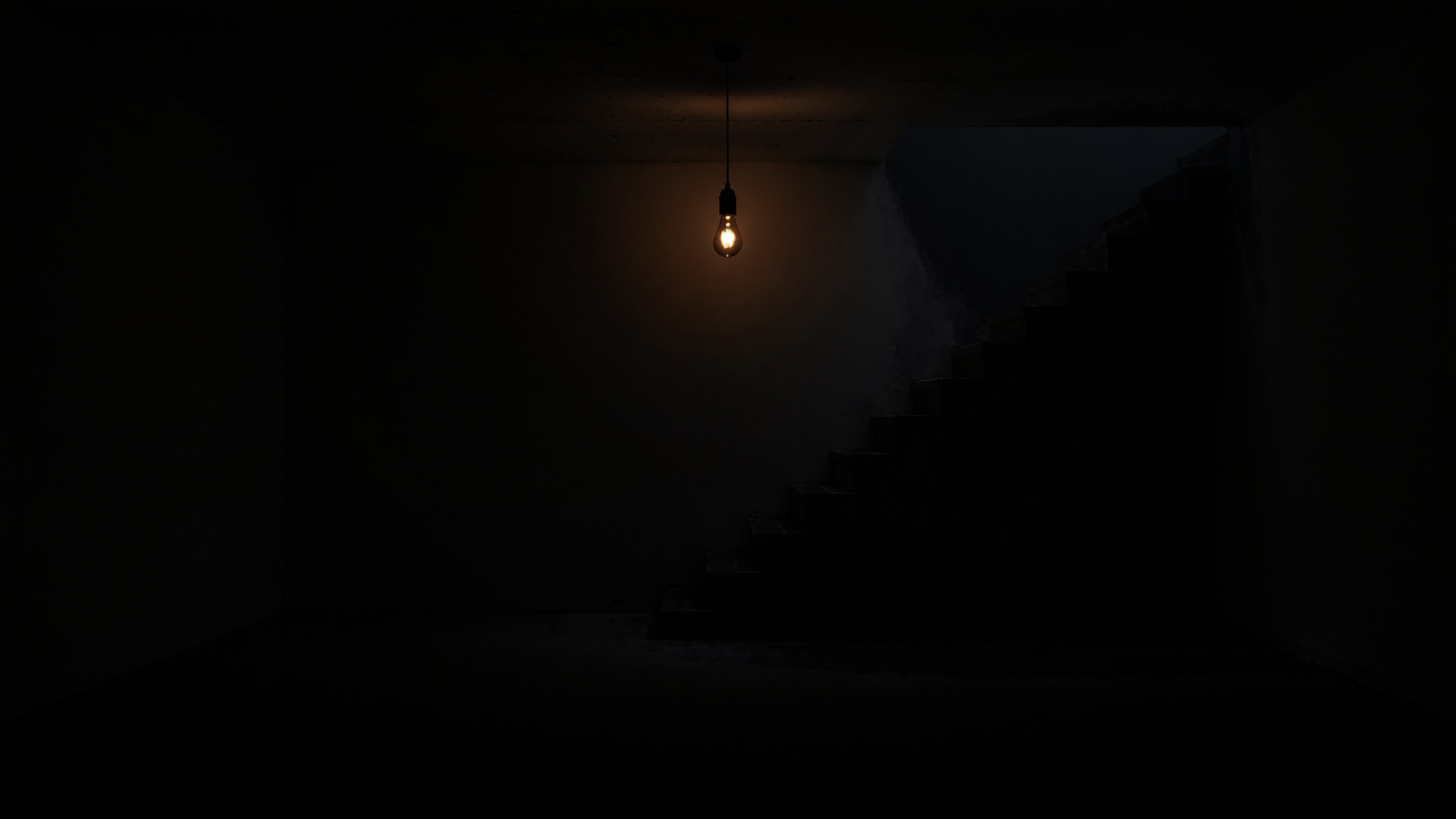 A dark empty basement: one weak bulb under the ceiling and a staircase along the back wall